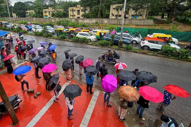 People holding umbrellas commute amid heavy showers in Bengaluru. (Photo source: PTI)