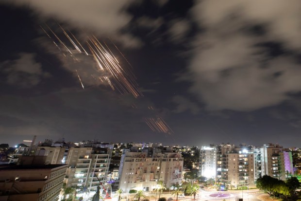 Israel's Iron Dome anti-missile system engaged in action, intercepting incoming rockets over Ashkelon. Bright flashes lit up the night sky as the system successfully targeted the projectiles, creating a dramatic display against the backdrop of the city.