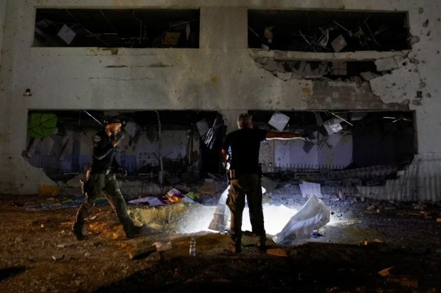 A member of the Israeli rescue force examines the site where a missile fired from Iran struck a school building in central Israel. (Reuters) 