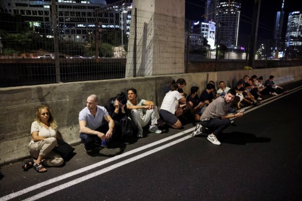 People took cover along the roadside as sirens blared in Tel Aviv, Israel, on October 1, following Iran's launch of a barrage of ballistic missiles aimed at the country. (Reuters) 
