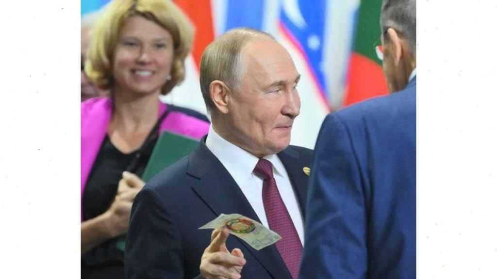 Putin holding the symbolic BRICS bank note at Kazan