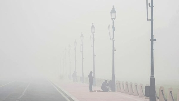 Workers fix a lamp-post along Kartavya Path, surrounded by dense smog and reduced visibility. (PTI)