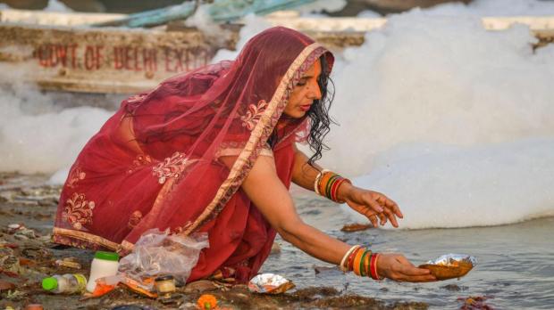 A devotee performs rituals along the banks of the Yamuna River, where toxic foam floats on the polluted surface, as the four-day Chhath Puja festival begins at Kalindi Kunj in New Delhi. (Image:PTI)