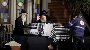 People stand next to the coffin of Israeli rabbi, Zvi Kogan, who was found murdered in the United Arab Emirates, during his funeral, in Kfar Habad, Israel, November 25, 2024. REUTERS