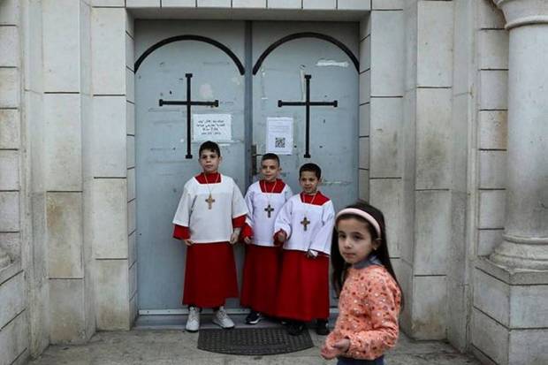 Children stand outside the Holy Family Church on Christmas Eve, amid the Israel-Hamas conflict, in Gaza City. (Photo source: Reuters)