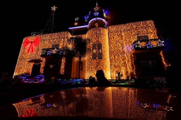 A man walks next to a car parked in front of a private residence decorated for Christmas with some 57,900 LED lightbulbs on its facade in Mosta, Malta. (Photo source: Reuters)