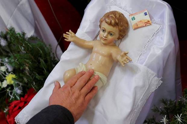 A devotee touches the statue of baby Jesus during the Christmas mass at St. Nicholas church in the Croatian minority town, in Janjevo, Kosovo December 25, 2024. (Photo source: Reuters)