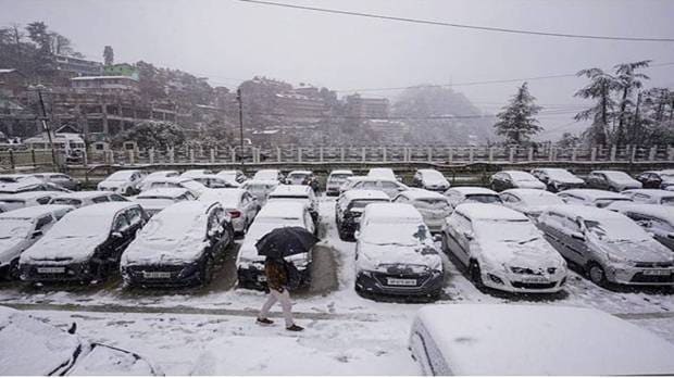 A man walks by parked cars covered with fresh snowfall, in Shimla. (Photo source: PTI)