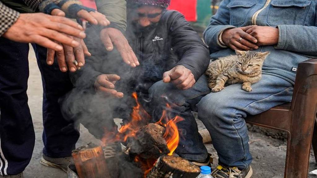 Boatmen warm themselves on a cold winter day, at the Dal Lake in Srinagar, Tuesday, Dec. 24, 2024. (Photo source: PTI)