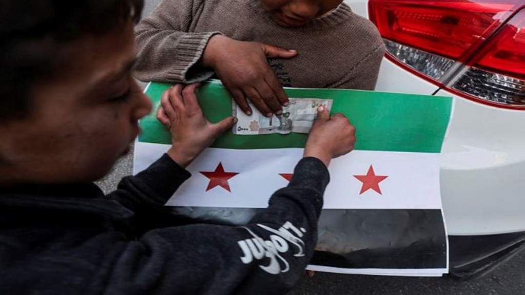 A boy sells pictures of the flag adopted by the new Syrian rulers, after the ousting of Syria's Bashar al-Assad, in Damascus, Syria, December 16, 2024. REUTERS/Amr Abdallah Dalsh