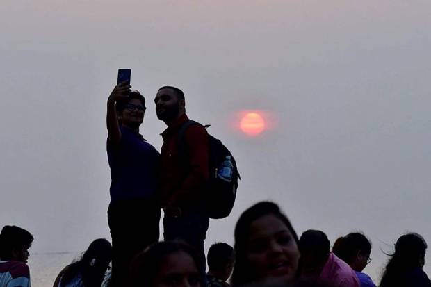 People click selfies against the last setting sun of the year 2024, at Marine Drive in Mumbai, Tuesday, December 31, 2024. (Photo source: PTI)q