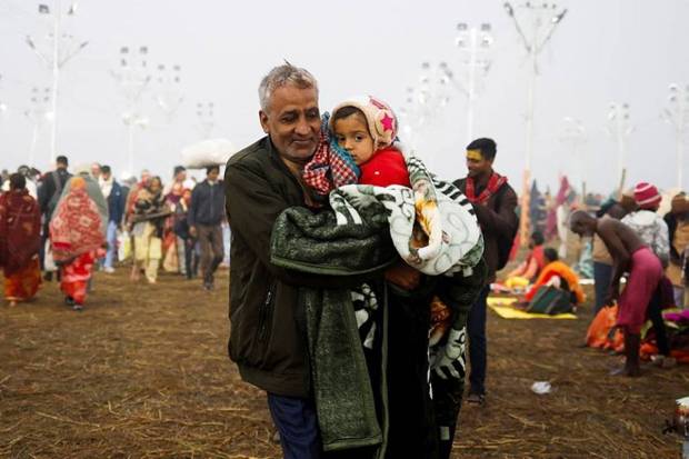 A devotee carries a child after taking a holy dip at Sangam. (Photo source: Reuters)