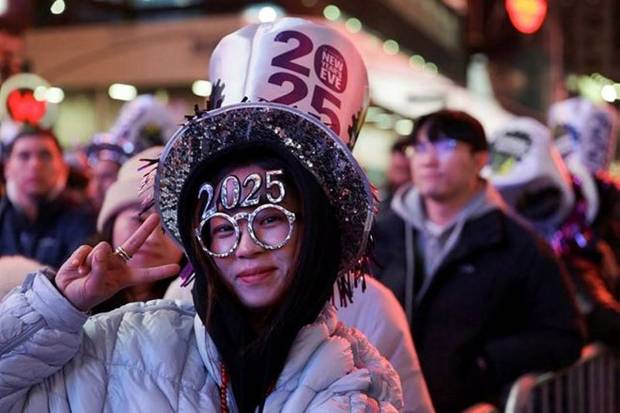 A woman gestures as people gather at Times Square to watch the ball drop on New Year's Eve in New York City, US.