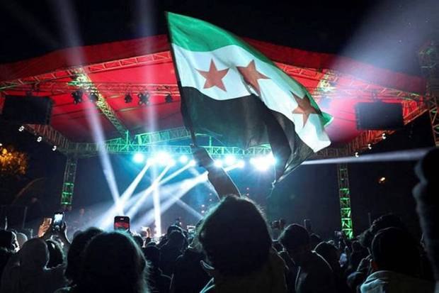 A flag is waved as people gather during New Year's celebrations, after the ousting of Syria's Bashar al-Assad, in Damascus, Syria. (Photo source: Reuters)