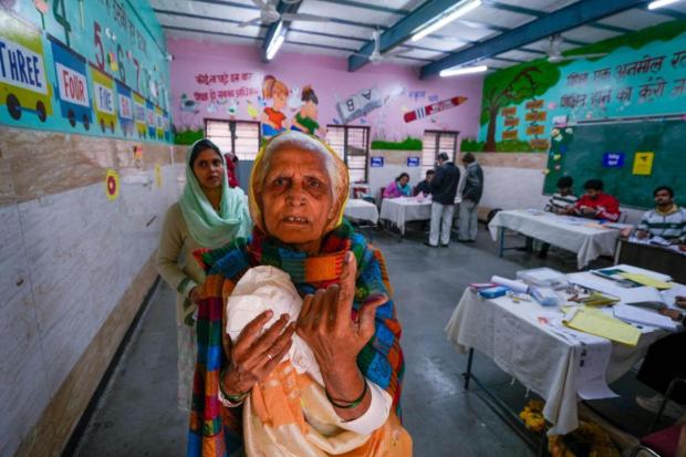 An elderly voter shows her finger marked with indelible ink after casting vote during the Delhi Assembly elections, at Trilokpuri.