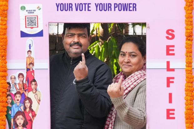Voters pose for pictures after casting vote during Delhi Assembly elections, at Lodhi Estate.