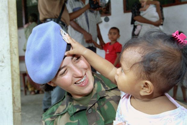 A United Nations Transitional Administration in East Timor (UNTAET) peacekeeper plays with a young child in Hera, East Timor. (Image: UN Photo)