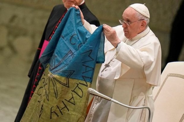 Pope Francis flashes a flag that was brought to him from Bucha, Ukraine, during his weekly general audience in the Paul VI Hall, at the Vatican on April 6, 2022. (Image Source: AP)
