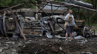 A resident with a dog stands next to cars destroyed in a residential area during a Russian drone strike, amid Russia's attack on Ukraine, in Odesa, Ukraine, May 25 (Photo: Reuters)