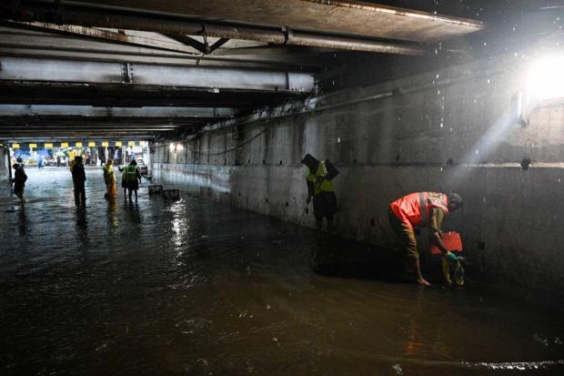 Workers clean the sludge at Andheri Subway as it has been waterlogged for a while due to this morning's rain, in Mumbai. (Express photo by Sankhadeep Banerjee)