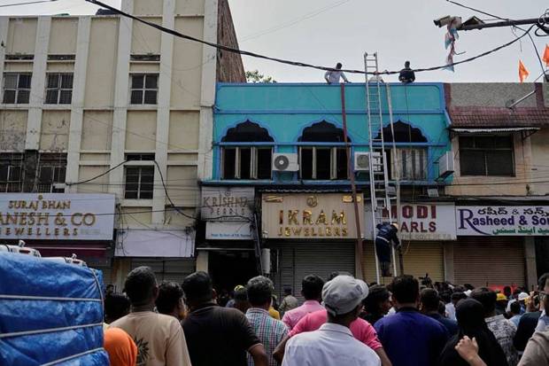 People watch as fire officials conduct rescue operations at a building following a fire in Hyderabad. (Photo source: AP)