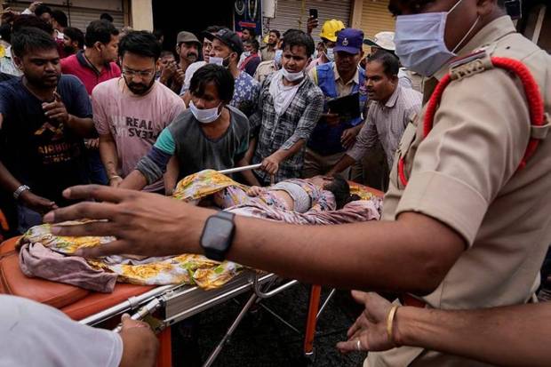Fire officials rescue an injured person from a building after it caught fire in Hyderabad. (Photo source: AP)