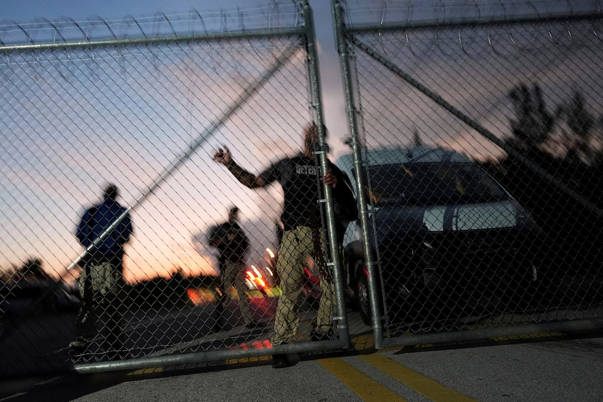 Krome Detention Center officers man an entrance gate as people hold a vigil outside to recognize those who have died in US Immigration and Customs Enforcement custody, as well as those affected by mass deportations, in Miami.
