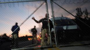 Krome Detention Center officers man an entrance gate as people hold a vigil outside to recognize those who have died in US Immigration and Customs Enforcement custody, as well as those affected by mass deportations, in Miami.