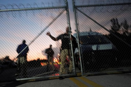 Krome Detention Center officers man an entrance gate as people hold a vigil outside to recognize those who have died in US Immigration and Customs Enforcement custody, as well as those affected by mass deportations, in Miami.