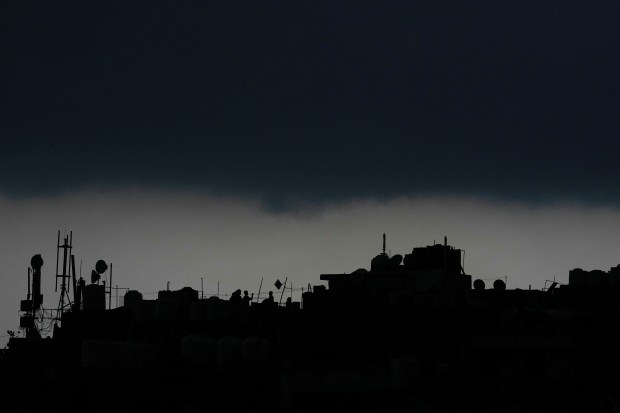 A boy flies a kite from the roof of his house as monsoon clouds gather over New Delhi’s skyline. (AP Photo)