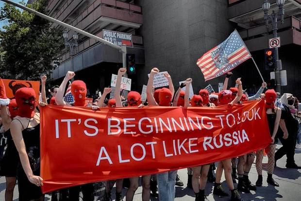Members of the Pussy Riot group carry a sign referring to Russia during a 
