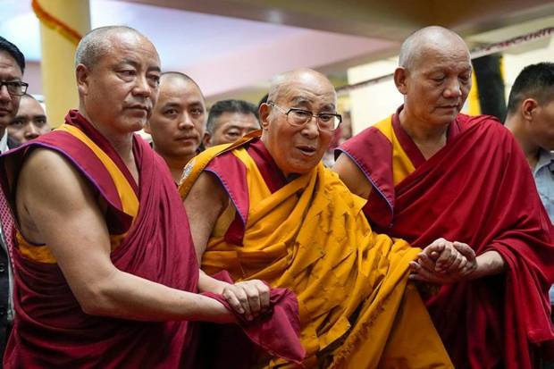 Tibetan spiritual leader, the Dalai Lama, being assisted by monks as he arrives for the long life prayer ceremony. (Photo source: AP)
