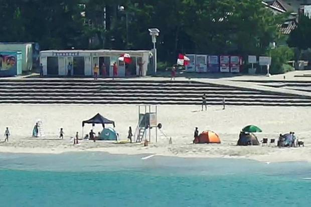 In this image taken from a fixed position video, people wave tsunami warning flags, seen in the background, to beachgoers immediately after a strong earthquake near Russia’s Kamchatka Peninsula, in Shirahama, Wakayama prefecture, western Japan Wednesday, July 30, 2025. (Photo source: AP)