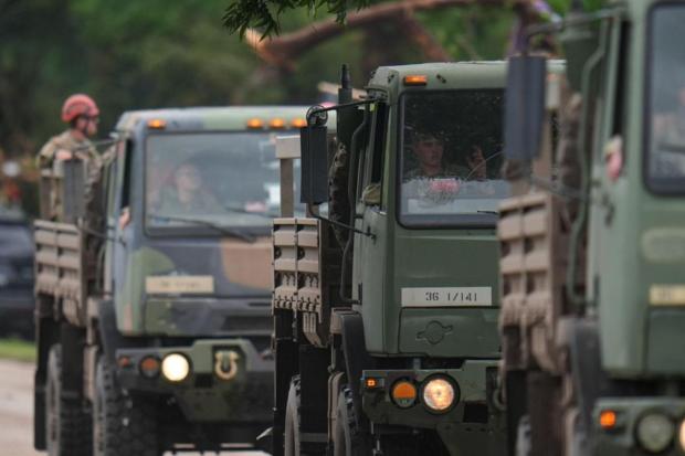 A military convoy drives on a road along the Guadalupe River following the flood.