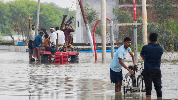 People take a ride on a tractor to move to a safer place at a village inundated with the Ganga river water, in Prayagraj, Uttar Pradesh. (Photo Source: PTI)