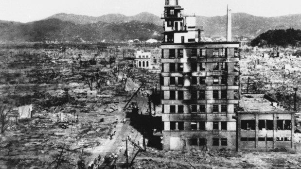 In this August 8, 1945, file photo, survivors walk past one of the few buildings still standing two days after an atomic bomb was dropped on Hiroshima, Japan, on August 6, 1945. (Photo Source: Associated Press)