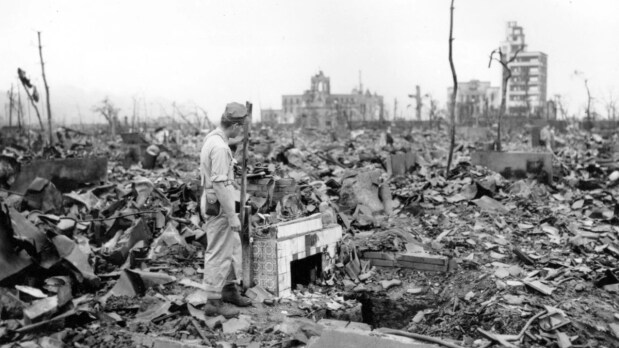In this September 7, 1945, file photo, an unidentified man stands next to a tiled fireplace where a house once stood in Hiroshima, Japan. In recollections published by the city years later, Gishi, a resident of Japan who witnessed the bombing, wrote that soldiers initially handled bodies carefully, one by one, but were soon overwhelmed by the huge number of decomposing corpses and used an incinerator originally intended for military horses. (Photo Source: Associated Press)