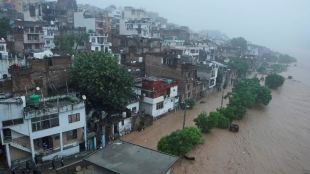 People watch a swelling River Tawi from the roof of their houses in Jammu | Representational image/AP