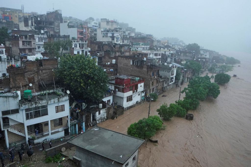 People watch a swelling River Tawi from the roof of their houses in Jammu | Representational image/AP