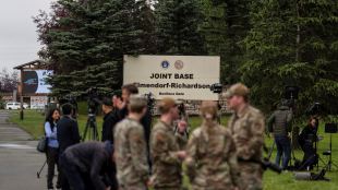 Military personnel and the media stand outside Joint Base Elmendorf-Richardson in Alaska ahead of a meeting between Donald Trump and Vladimir Putin. (AP Photo)