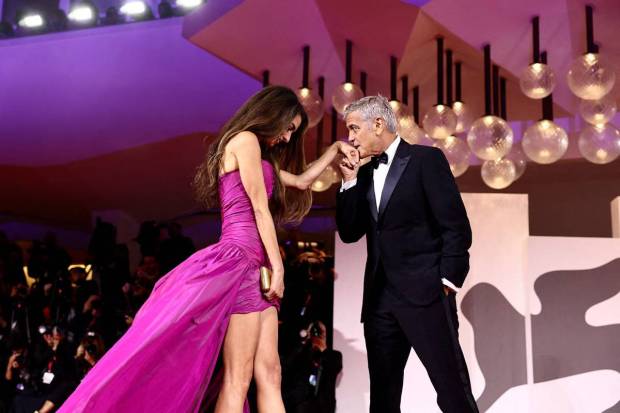 Cast member George Clooney kisses the hand of his wife Amal Clooney on the red carpet for the screening of 