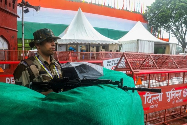 A security personnel keeps vigil amid rainfall near Red Fort area in New Delhi on the eve of Independence Day. (Image source: PTI)