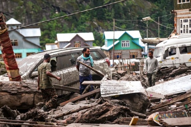 People stand amidst the debris at an affected area after a cloudburst in Kishtwar district, Jammu and Kashmir. (Image source: PTI)