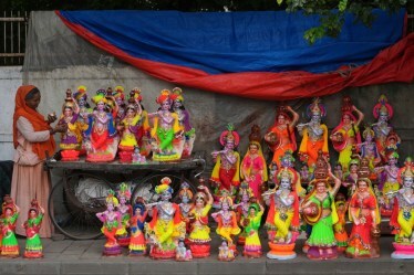 A woman selling idols of Hindu god Krishna and his consort Radha gives finishing touch to an idol ahead of Janmashtami, the festival that marks the birth of Krishna, in Ahmedabad. (Image source: AP)