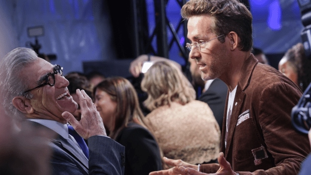 Eugene Levy (from left), sharp in a white suit, catches up with Ryan Reynolds at Roy Thomson Hall, both honoring Toronto legend John Candy at the festival’s acclaimed documentary premiere.