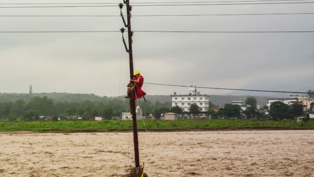 Following the destruction, the district administration, the State Disaster Response Force (SDRF), and police were immediately dispatched to the distress site to provide relief and rescue operations. (In Frame: An NDRF personnel rescues a man stranded on an electric pole as a river flows in spate following a cloudburst, near Prem Nagar in Dehradun) (Photo Source: PTI)