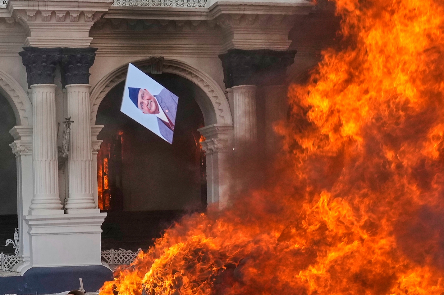 A protester throws a photograph of Nepal Prime Minister Khadga Prasad Oli in the fire at Singha Durbar, the seat of Nepal's government's various ministries and offices (Photo: AP/PTI)