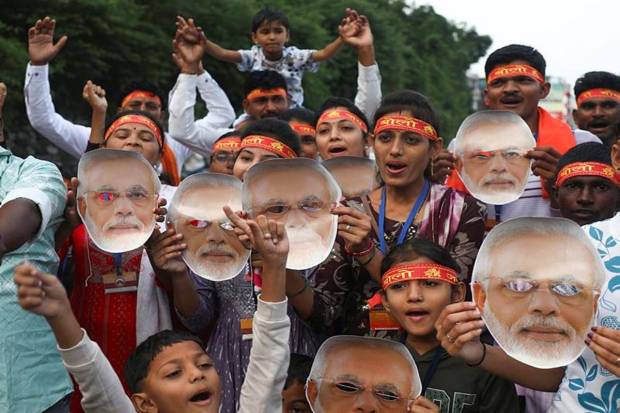 Pilgrims chant religious slogans while carrying masks of PM Modi  on his birthday as they prepare to leave for Mata Vaishno Devi shrine, at Darshani Deodi, Katra, in Reasi district, Jammu and Kashmir. (Photo source: PTI)