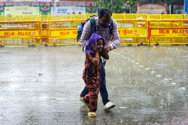 A father and daughter are seen walking together through heavy showers, carefully making their way as the rainfall continues to drench the surroundings. (Image: ANI)
