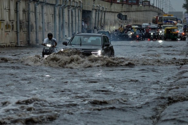 People can be seen making their way through steady rainfall, adjusting to the wet weather conditions while continuing with their daily routines. (Image: PTI)